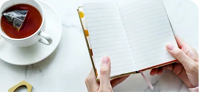 A cup of tea beside an open journal