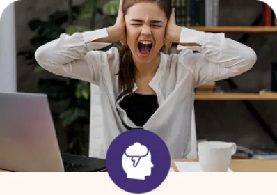 A person covering their ears at a desk, representing PTSD distress